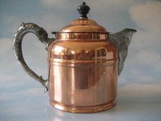 an antique copper coffee pot with two birds on it