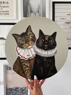 a person holding up a plate with two cats on it and one cat wearing a collar