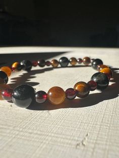 The Black Tourmaline, Garnet, Orange Calcite, and Yellow Tiger's Eye bracelet is a cornerstone of stability and grounding, meticulously crafted to foster a deeply rooted sense of balance and protection. It is a harmonious assembly of crystals, each selected for its unique ability to connect the wearer to the earth's energy and to shield the spirit from external disturbances. Black Tourmaline, with its deep black hues, acts as a powerful grounding force, offering unmatched protection against nega Spiritual Round Amber Bracelet, Amber Bracelets With Natural Stones, Amber Gemstone Bracelet For Healing, Spiritual Amber Bracelet With Natural Stones, Spiritual Amber Bracelets With Natural Stones, Amber Bracelets With Natural Stones For Meditation, Hand-strung Amber Crystal Bracelet For Healing, Healing Bracelet With Stones, Grounding Crystals