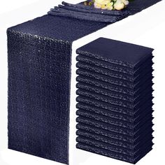 a stack of blue napkins sitting on top of each other next to a vase with flowers