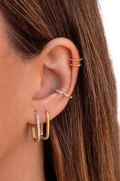 a woman wearing two gold hoop earrings with small diamonds on the inside of her ear