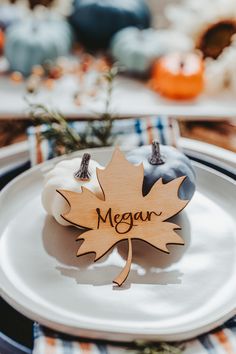 a white plate topped with a wooden maple leaf and an acorn on top of it