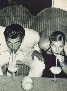 an old photo of two people drinking cocktails