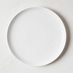 an empty white plate sitting on top of a table