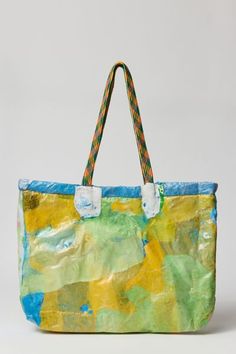 a handbag made out of paper and rope with colorful paint on the inside, in front of a white background