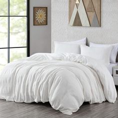 a bed with white comforter and pillows in a room