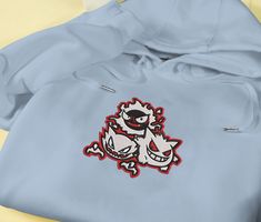 Introducing our Ghost Gengar Embroidered Hoodie, the perfect addition to your Pokémon collection. This sweatshirt features a meticulously crafted embroidered Gengar design, showcasing its mischievous nature. Made from premium quality materials, it ensures utmost comfort and durability. Whether you’re a die-hard Pokémon fan or looking for a unique gift, this hoodie is bound to impress. Embrace the dark side with style and make a statement wherever you go. Elevate your fashion game with our Hooded Hoodie With Machine Embroidery For Streetwear, White Hooded Hoodie With Embroidered Patch, Casual Hooded Hoodie With Machine Embroidery, Long Sleeve Hoodie With Machine Embroidery For Streetwear, Long Sleeve Hoodie With Embroidery For Streetwear, Cotton Hoodie With Machine Embroidery, Hooded Cotton Tops With Machine Embroidery, Casual Hoodie With Machine Embroidery For Streetwear, Casual Embroidered Hoodie For Streetwear