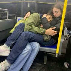 two people sitting on a bus with their arms around each other as they are hugging