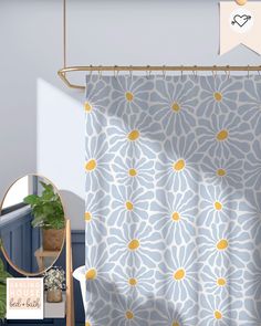 a shower curtain with yellow and blue flowers on it in front of a mirror next to a potted plant