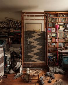 a room filled with lots of clutter and bookshelves next to a window