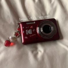 a red camera key chain laying on top of a bed