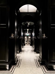 the hallway is lined with black wood paneling and gold lamps on either side of it