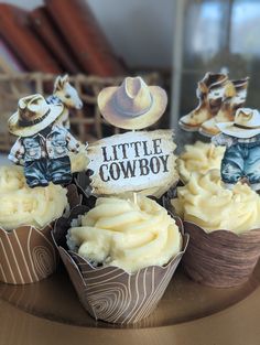 some cupcakes with cowboy decorations on top of them are sitting on a table