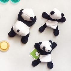 three stuffed panda bears sitting on top of a table next to buttons and magnets