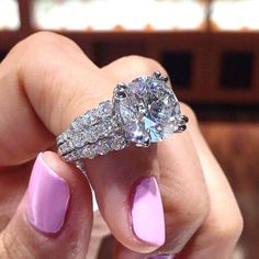 a woman's hand holding a pink manicured nail with a diamond ring on it