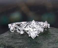 an engagement ring with three princess cut diamonds in the center on top of a rock