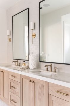 a bathroom with double sinks and two mirrors on the wall next to eachother