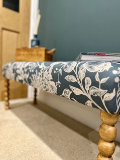 a wooden bench with a blue and white floral seat cover on it's legs