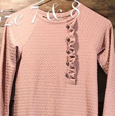 a pink sweater with ruffles and buttons on it