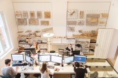 three people sitting at desks working on computer screens in an office setting with multiple monitors and keyboards