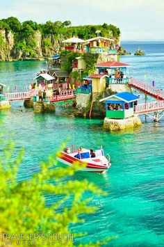 boats floating on the water in front of colorful houses and piers at an island