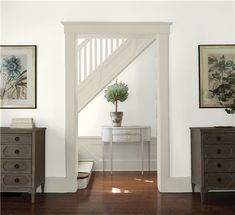 an entry way with two dressers and a potted plant on the table next to it