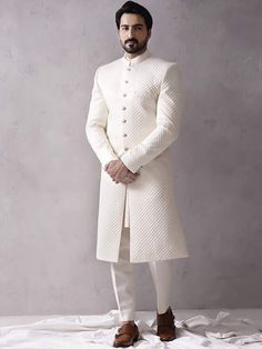 Item Contains:  Sherwani kurta and Pants   Color :  white Fabric :  Quilted silk fabric Style and Designs :  sherwani has mandarin collar and long sleeves with a full button placket even hem and multiple straight slits Kurta has mandarin collar and long sleeves with symmetric hem and multiple slits Pants boot cut style pants with 2 pockets and a fly on zip and hooks  Size :  Slim fit  Model height is 6 fit and wearing 40 size  Material and Care :  Polyester mix  Only dry clean  Note :  There mig White Long Bandhgala For Eid, White Long Sleeve Traditional Winter Wear, Fitted White Sherwani With Dabka Details, Festive White Sherwani For Winter, White Fitted Sherwani For Winter, White Bandhgala For Formal Winter Events, Fitted White Winter Sherwani, White Long Sleeve Bandhgala For Winter, Festive White Sherwani