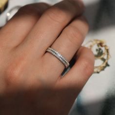 a woman's hand with a diamond ring on her left hand and the other hand holding an object