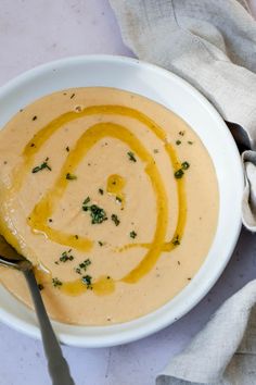 a white bowl filled with soup on top of a table next to a silver spoon