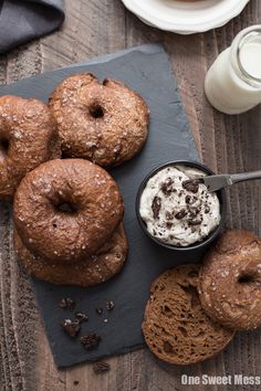 chocolate donuts with whipped cream and cookies on a slate board next to a glass of milk