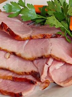 slices of ham on a plate with carrots and parsley