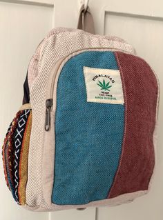 Small Rucksack made with Himalayan Hemp & Cotton with Gheri side pockets. The front panel is Blue and Brown Hemp with 'Himalayan Hemp' logo and fastens with a zip. The main bag has a zipped fastening and is made with woven cotton and there are two multicoloured Gheri fabric side pockets with elastic tops. The interior is lined with black fabric and has a small zipped pocket. Measurements:  Width: 30 cm. Length: 35 cm. Straps: 90 cm.(When fully extended) Strap width: 5 cm. HANDMADE & FAIRTRADE. Y Standard Backpack With Side Pockets, Casual Blue Backpack For Adventure, Casual Blue Adventure Backpack, Outdoor Backpack With Side Pockets, Backpack With Side Pockets For Daily Use, Daily Use Backpack With Side Pockets, Patchwork Backpack For School, Casual Patchwork Backpack, Outdoor Activities Backpack With Side Pockets