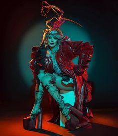 a woman sitting on top of a chair wearing high heels and a red jacket with feathers