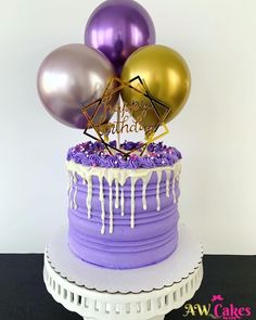 a birthday cake with purple icing and gold balloons