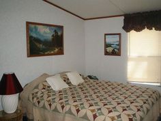 a bed in a room with two paintings on the wall and a lamp next to it