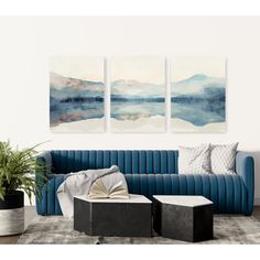 three paintings hang on the wall above a blue couch and coffee table in a living room