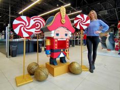 a woman standing next to two giant candy canes and a nutcracker statue