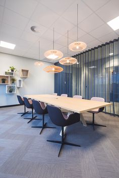 an empty conference room with several chairs and lights hanging from the ceiling, along with large windows