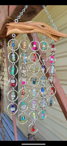 a metal wind chime hanging from a wooden pole with beads and chains attached to it