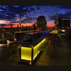 the rooftop bar is lit up at night with city lights and skyscrapers in the background