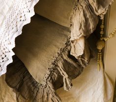 a close up of pillows on a bed with lace and crocheted doily