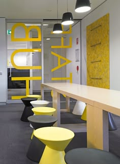 an office with yellow and gray chairs, tables and lamps on the ceiling is decorated with letters that spell out happy