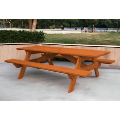 a wooden picnic table sitting on top of a cement floor