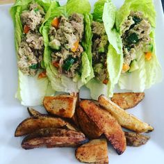 three lettuce wraps with chicken and french fries on a white plate, ready to be eaten