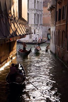 several gondolas are floating in the water near buildings and people on small boats