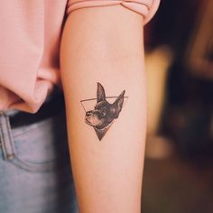 a small dog tattoo on the left forearm and arm, with an arrow in the center