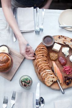 a person is holding their hand over a platter with bread, cheese and fruit