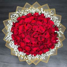 a bouquet of red roses and baby's breath arranged in a heart - shaped arrangement