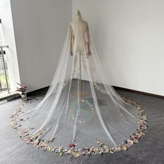 a wedding dress on display in a room with flowers all over the floor and around the neckline