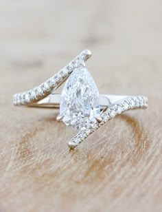 a pear shaped diamond ring on top of a wooden table